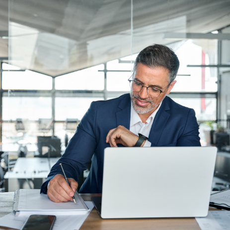 man on computer taking notes