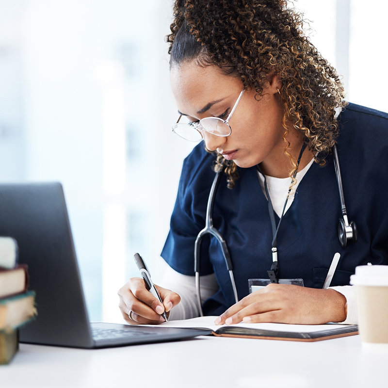 woman writing next to laptop